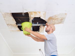 Man-Collecting-Water-in-Bucket-Water-Leak