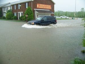 floods and water damage restoration tips for you and your family - SUV driving through water on a flooded road