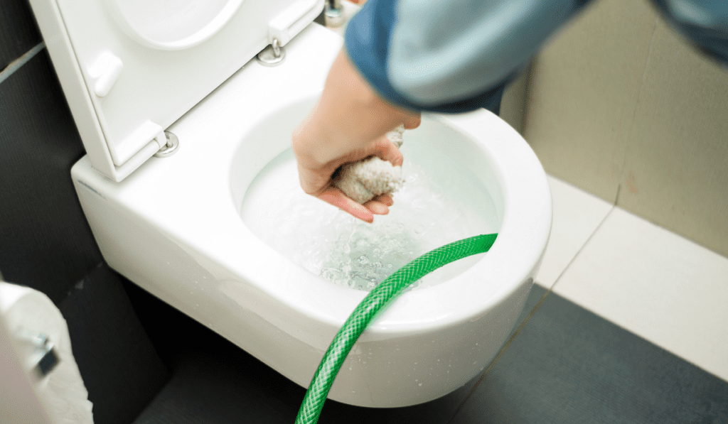How do homeowners safely clean the toilet overflow