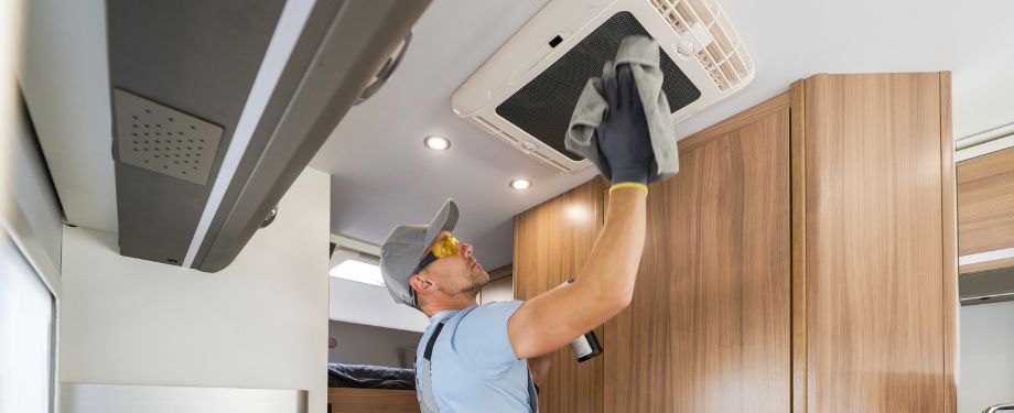 RV Rental Company Worker Cleaning Motorhome Air Condition Unit