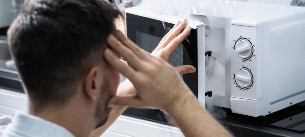 Man Looking At Fire Coming From Microwave Oven