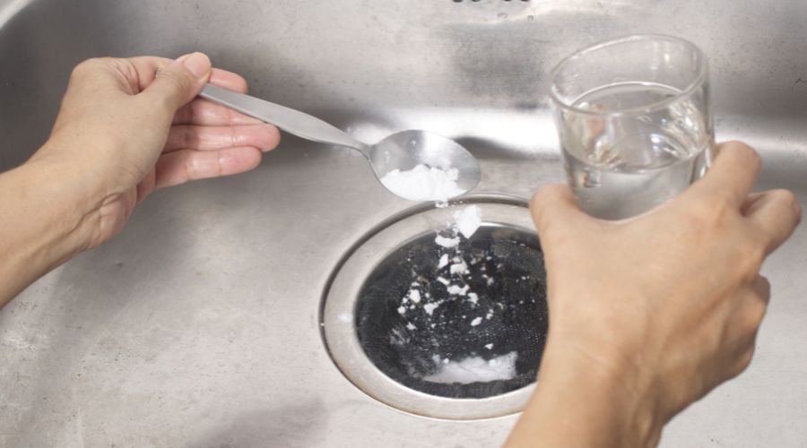 man pouring baking soda and hot water in the sink