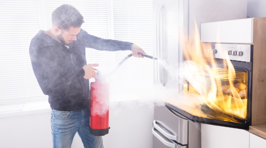 man using fire extinguisher to put out a fire
